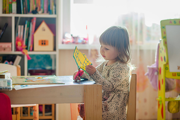 little girl practicing her scissor skills during craft time