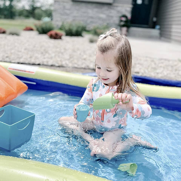 little girl playing with sensory water toys in a kiddie pool