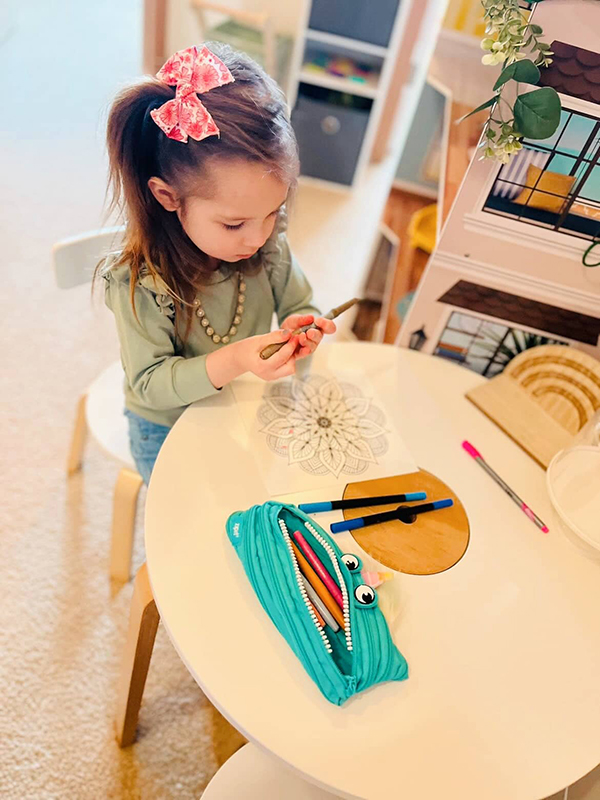 little girl collecting pencils in her blue unicorn zip pouches