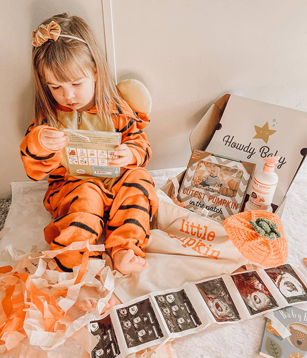 toddler girl opening the October 2023 Howdy Baby subscription box