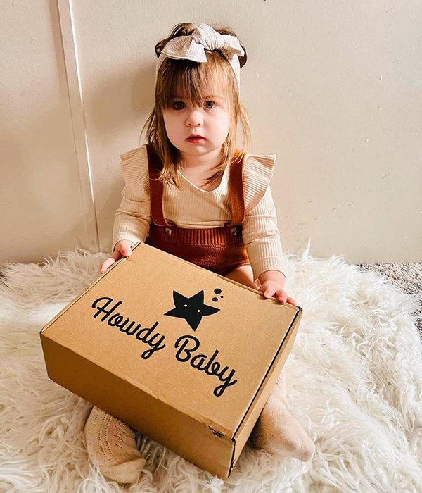 little girl holding her monthly subscription box for families