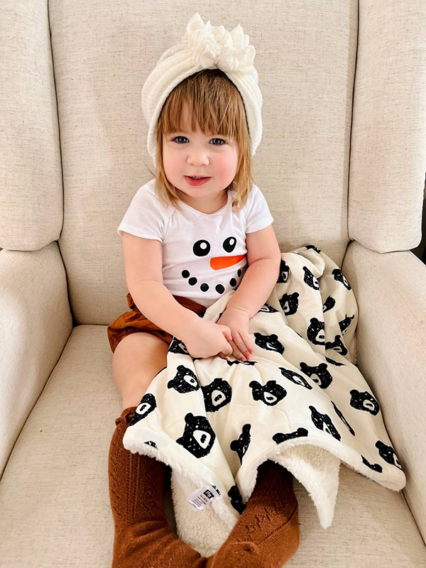 toddler girl with a toddler plush winter bear print blanket