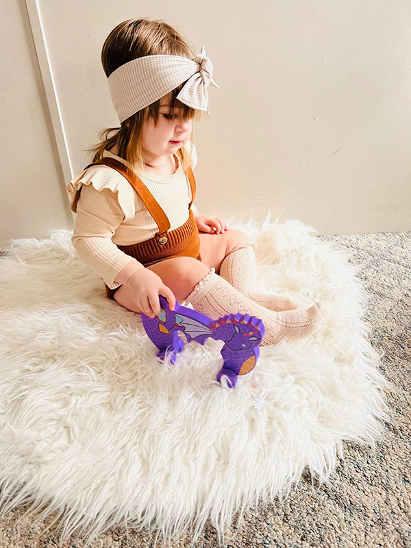 Howdy Baby toddler subscription box customer playing with wooden dragon toy