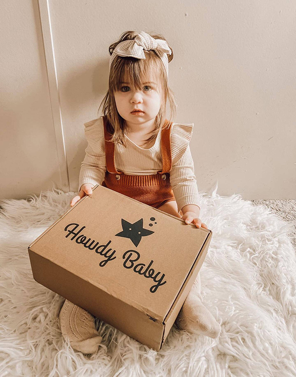 toddler girl getting ready to open her Howdy Baby subscription box