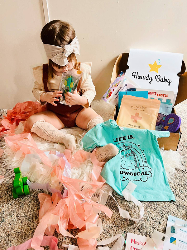 baby girl opening her March 2023 Howdy Baby toddler subscription box