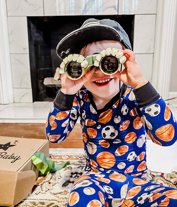 little boy looking through a pair of toy binoculars for kids