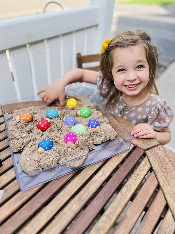 little girl playing with a wooden ladybug play set