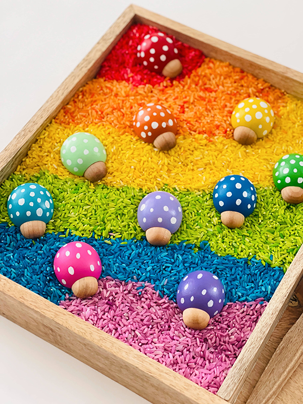 wooden ladybugs in rainbow colored sensory bin for kids