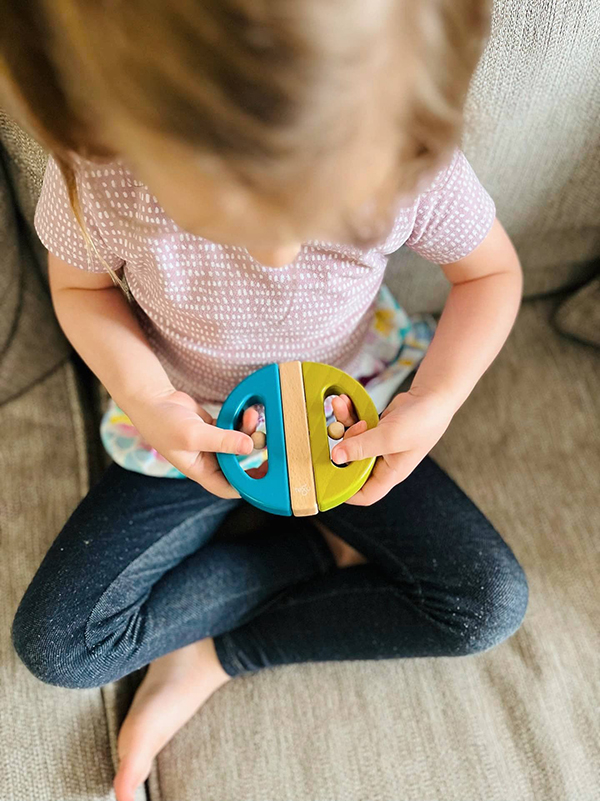 little girl playing with a wooden swivel bug Montessori toy