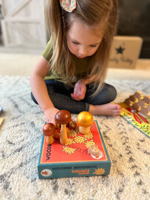 little girl playing with wooden mushroom toys