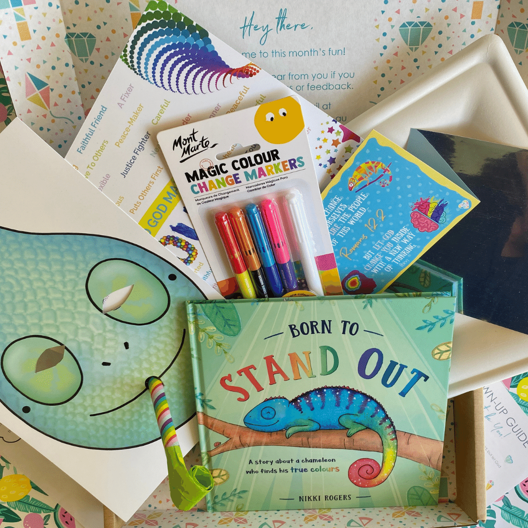 Open subscription box filled with items for Christian kids to explore how God made them, including Christian children's book Born to Stand Out by Nikki Rogers and chameleon mask. 
