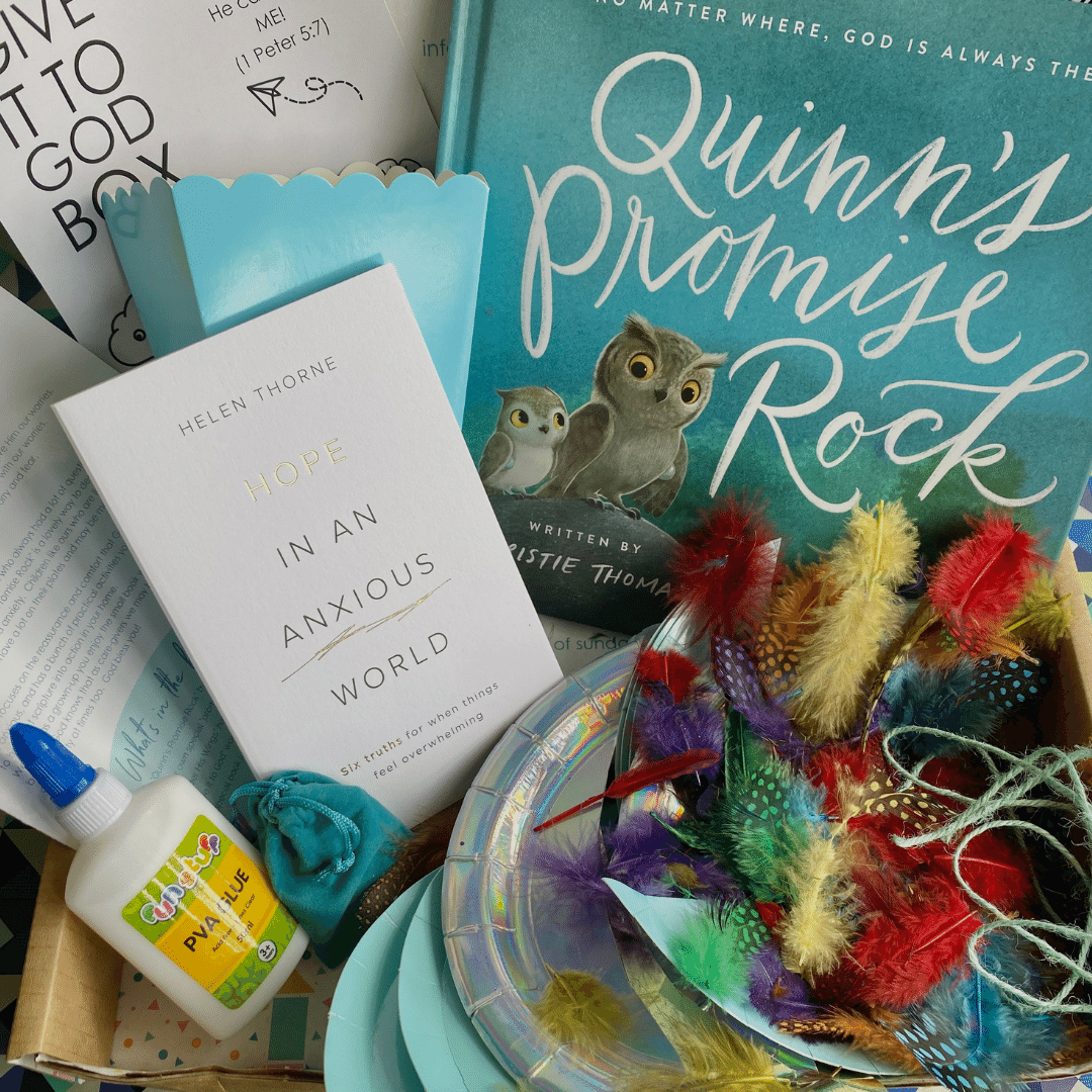 Open subscription box filled with colourful items, Christian book called Quinn's Promise Rock, and feathers for bible craft about worrying.