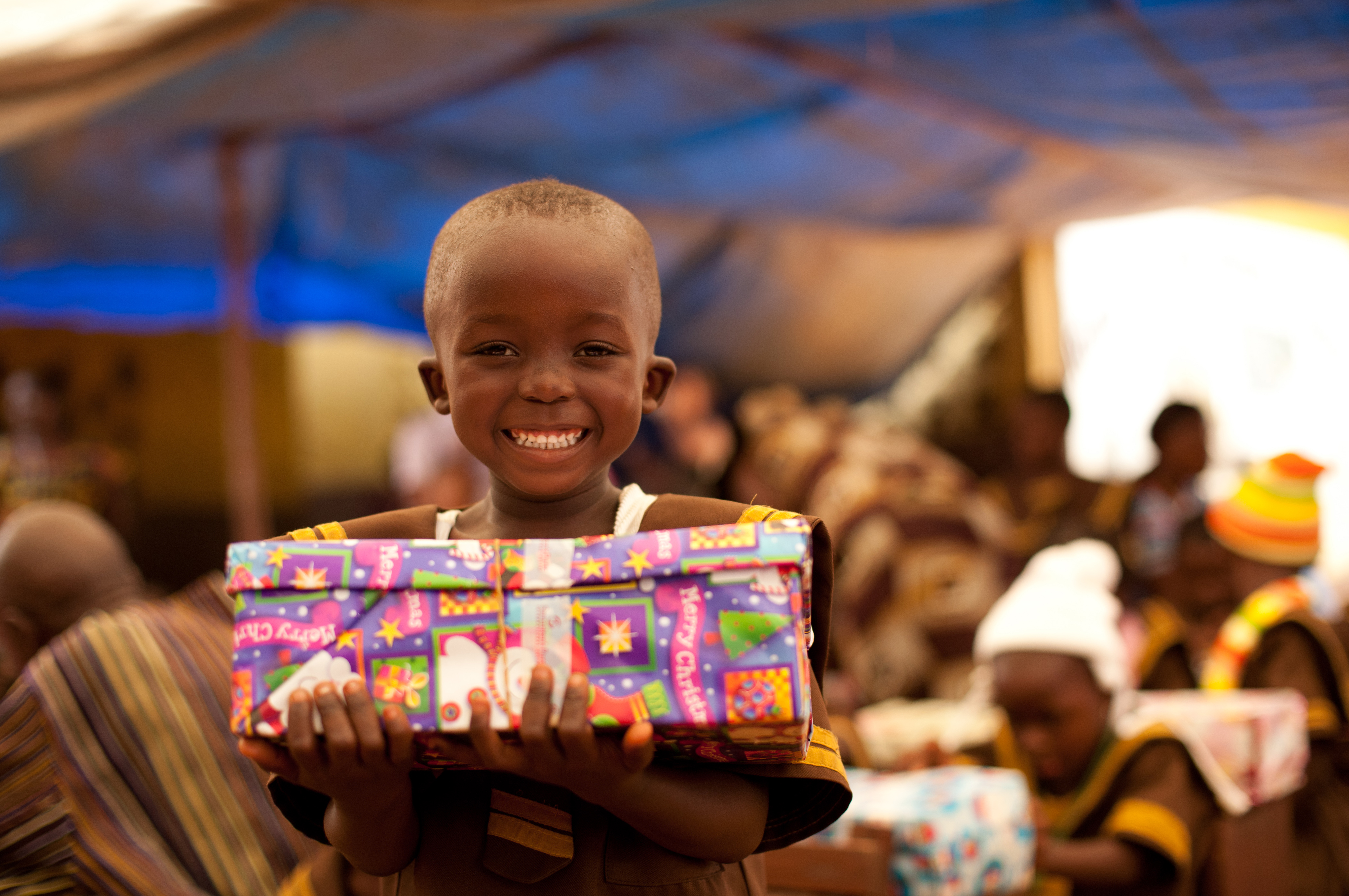 Child from Liberia smiling holding a Christmas shoebox present. 
