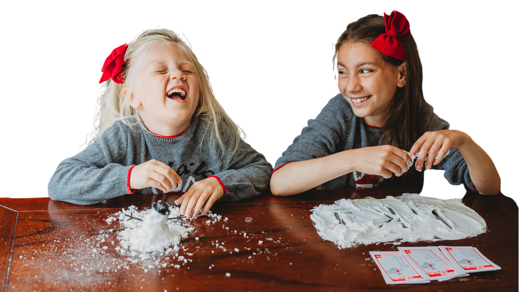 Preschool girl, head back, eyes clothed, laughing, playing with My Pre-K Box sensory snow, sister looking at her laughing, playing writing letters in sensory snow