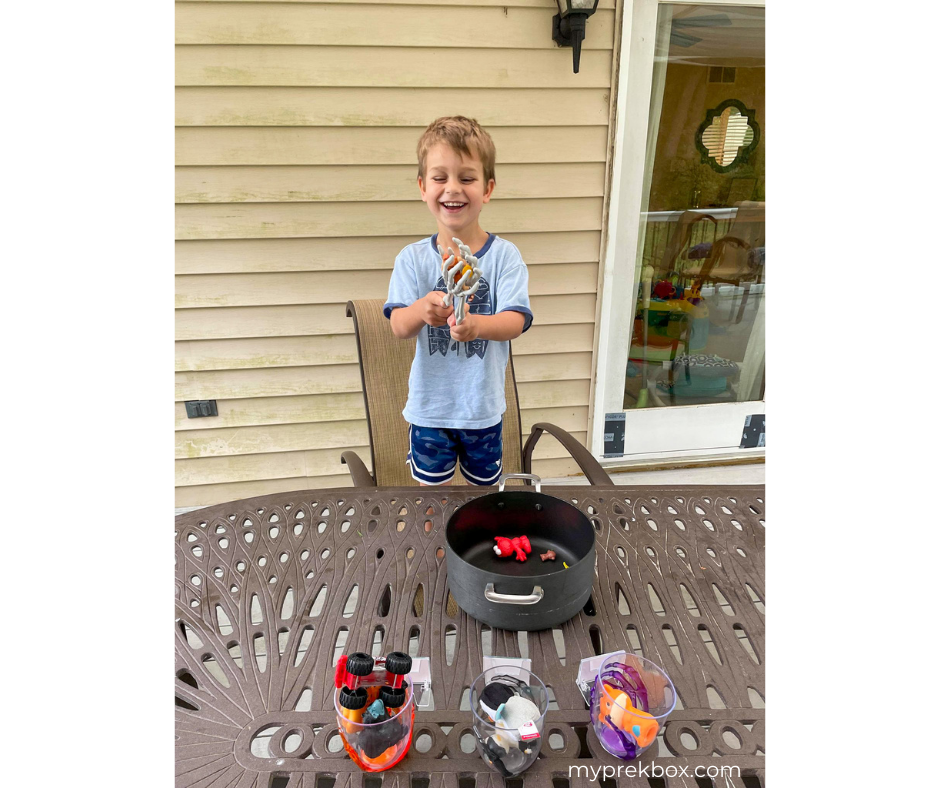 Preschool Halloween Literacy Activity, boy picking up toy from pot with skeleton hands