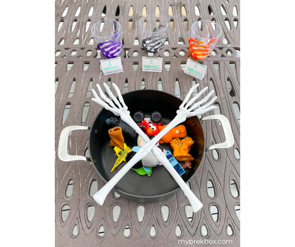 Preschool Halloween Literacy Activity, pot with toys, skelton hands, and cups