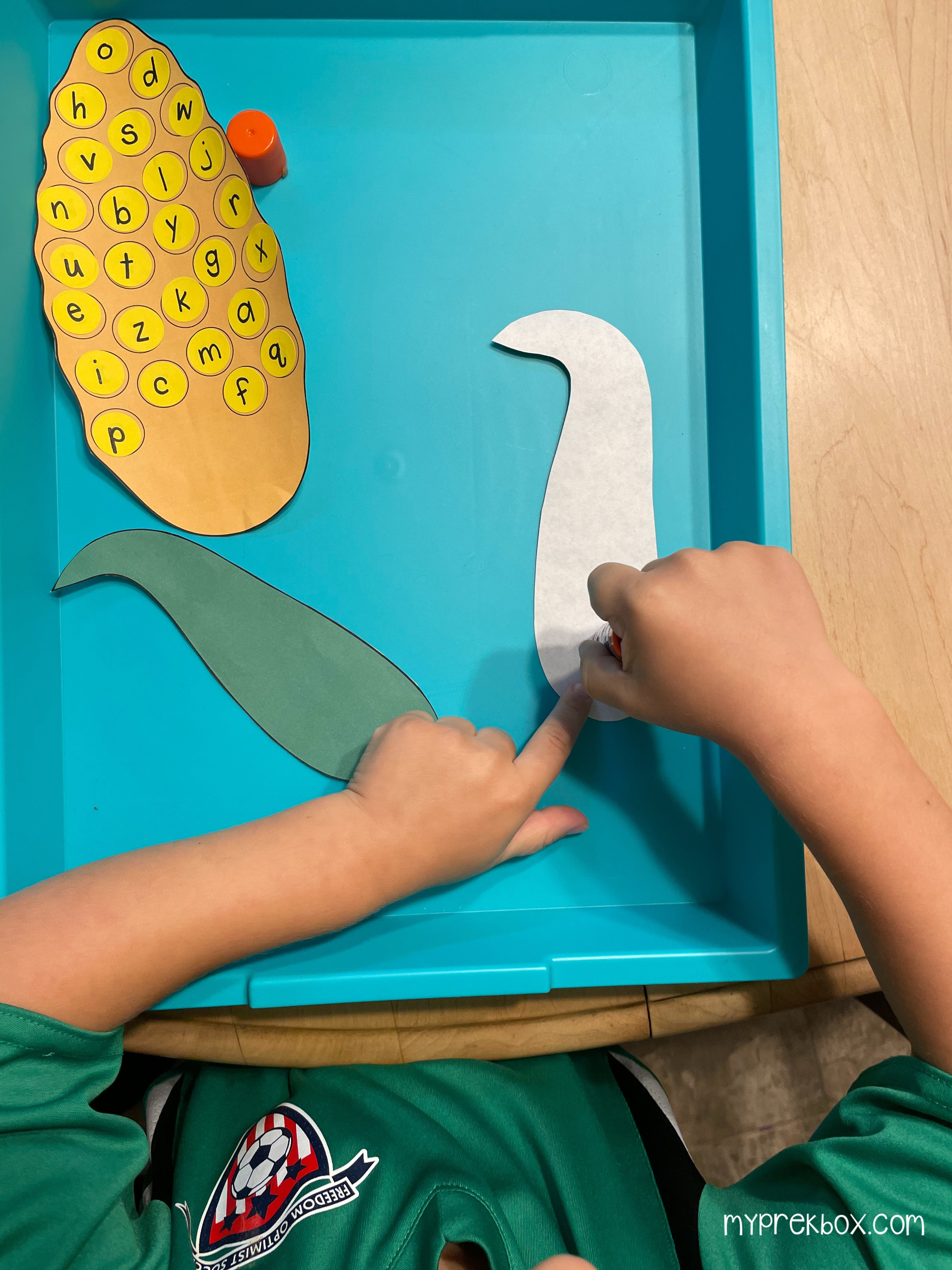 child gluing leaves on corn cob