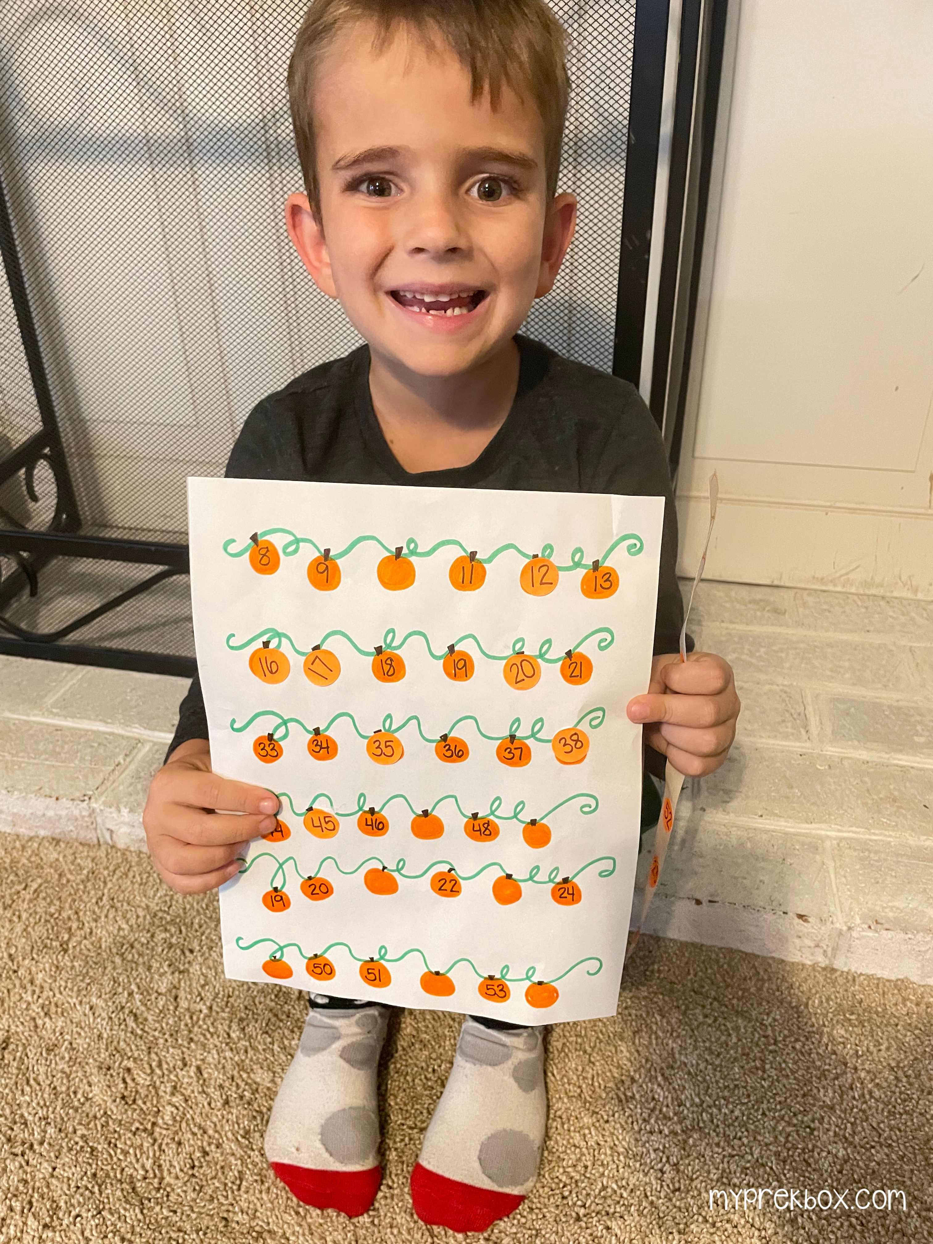 child holding completed pumpkins on a vine