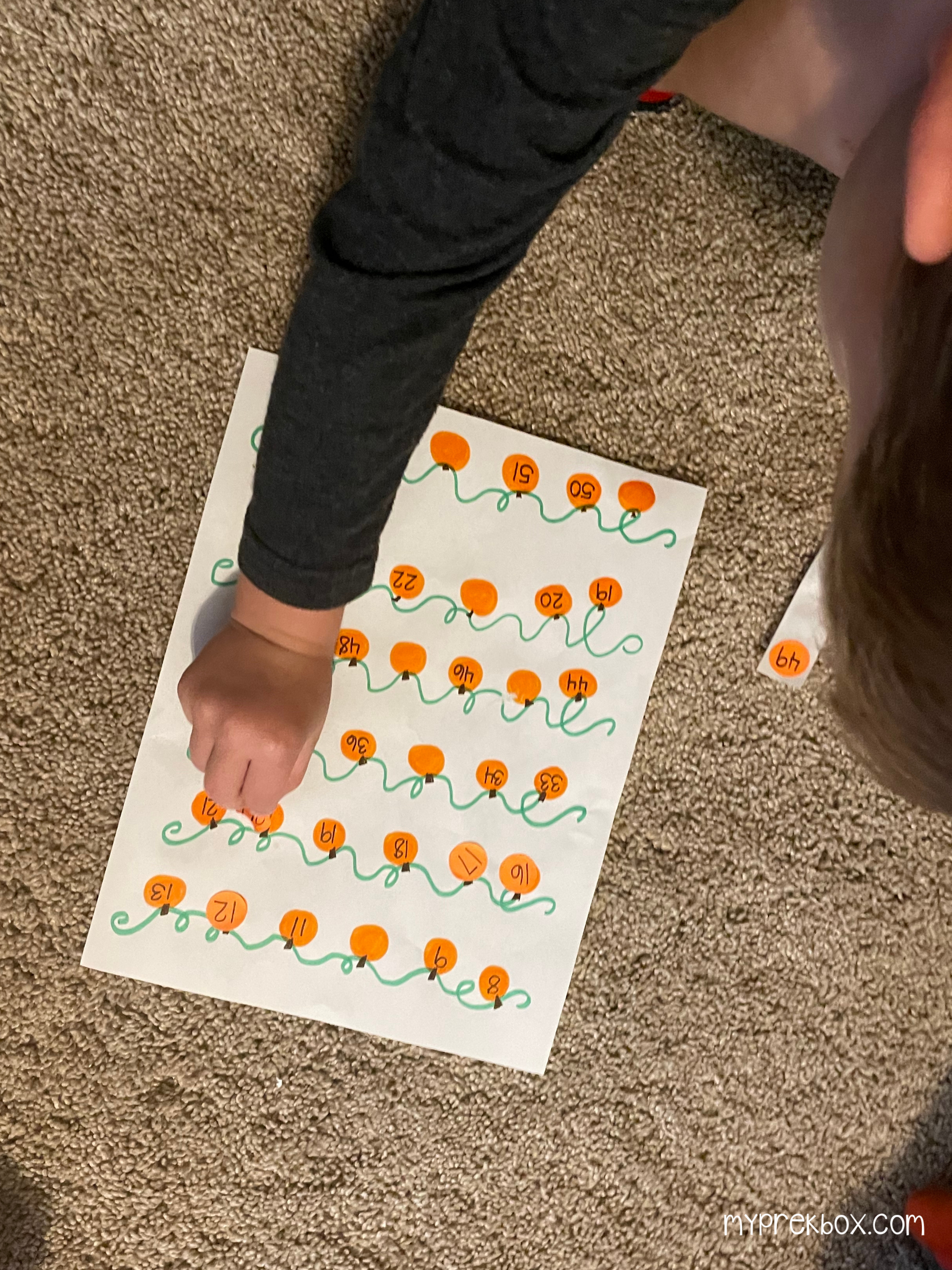 child putting numbered stickers on pumpkin vine