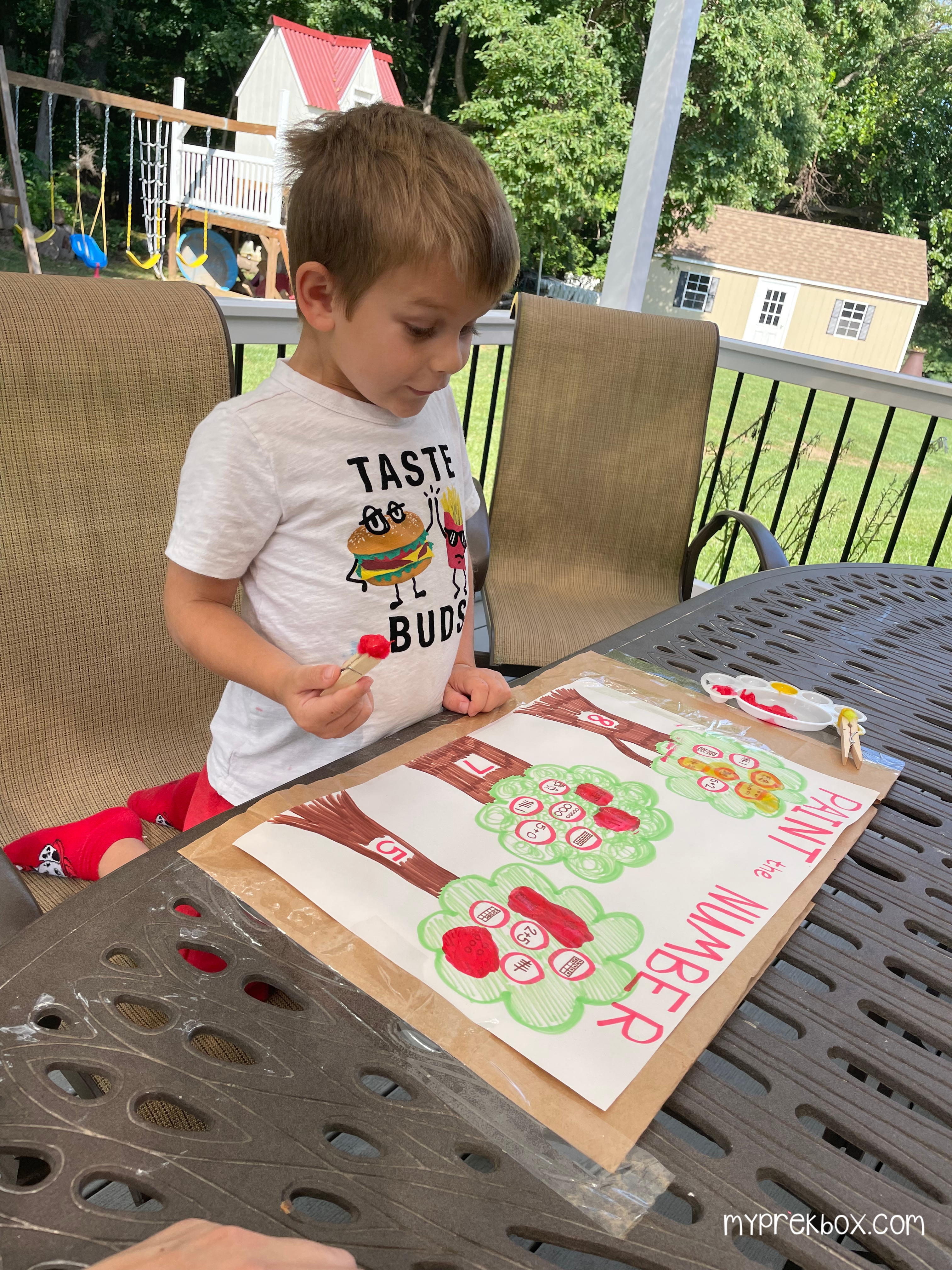 excited kid painting numbers with pom pom