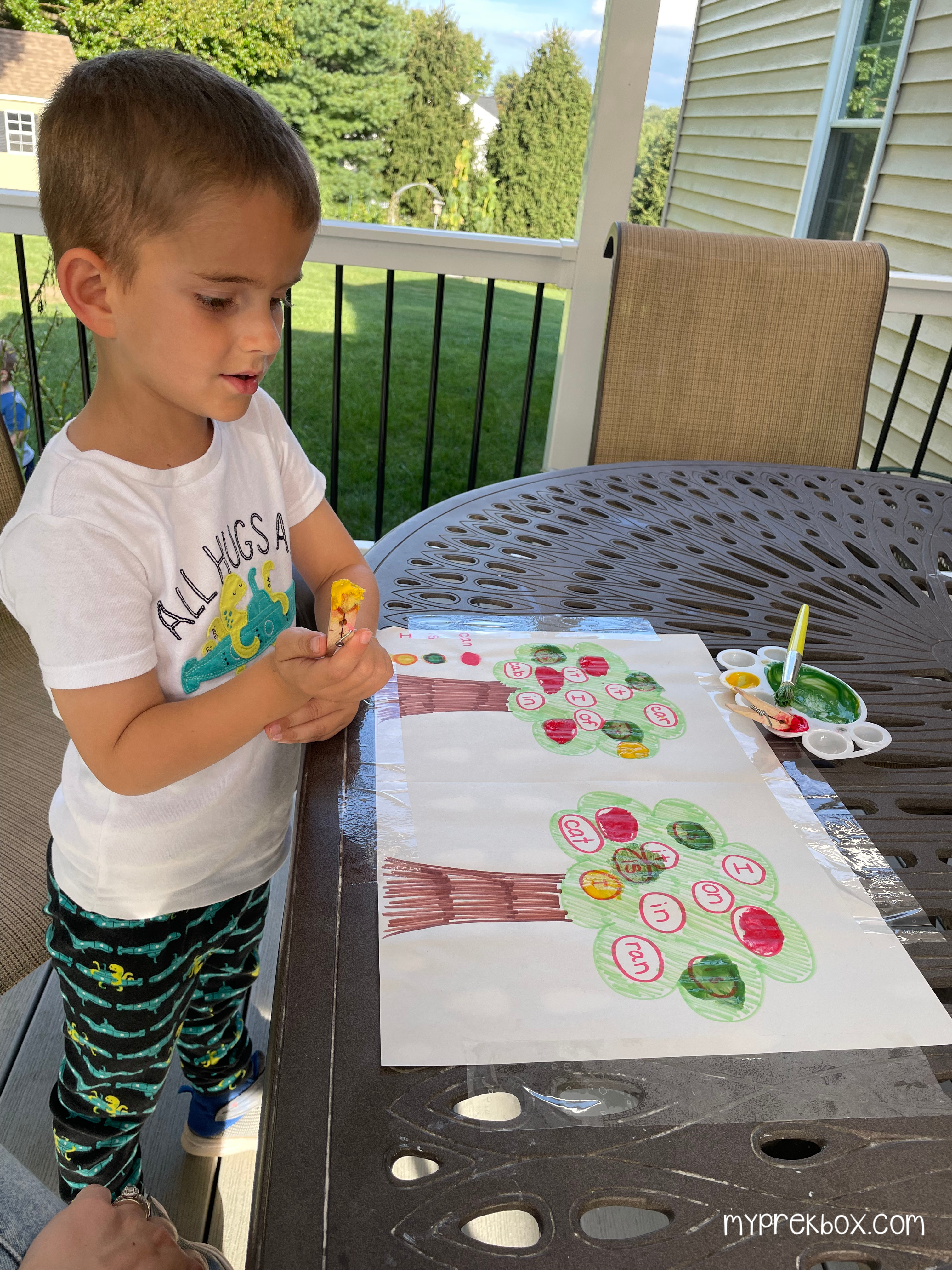 kid painting sight words on tree