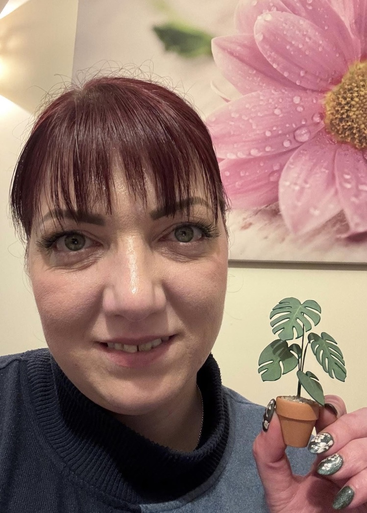 Miniature Monstera Deliciosa made with a Nicole’s Jungle kit Smiling woman holding a miniature handmade paper Monstera Deliciosa plant in a terracotta pot