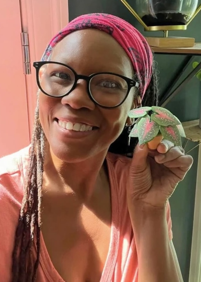 Handmade Caladium paper plant from Nicole’s Jungle Smiling woman holding a handmade miniature Caladium paper plant, surrounded by hanging greenery