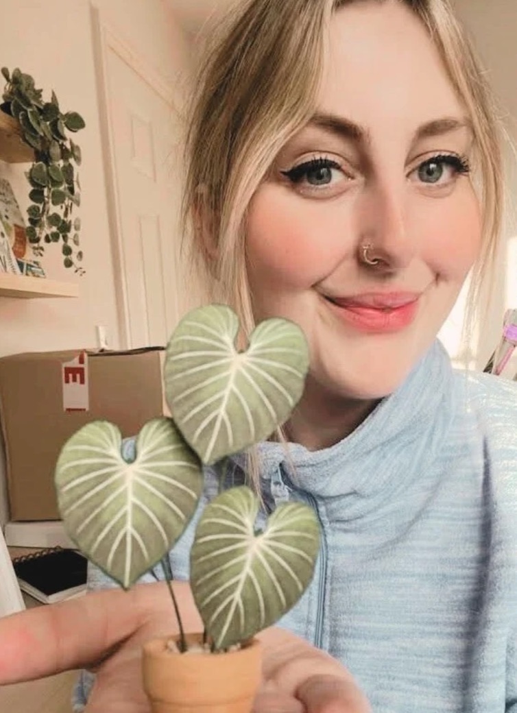 Miniature Philodendron Gloriosum paper plant made with a Nicole’s Jungle kit Smiling woman holding a miniature handmade paper Philodendron Gloriosum plant with heart-shaped leaves