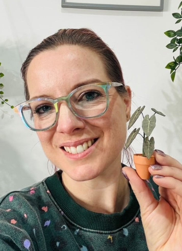 Miniature Alocasia Frydek paper plant made with a Nicole’s Jungle kit Smiling woman holding a miniature handmade paper Alocasia Frydek plant in a terracotta pot