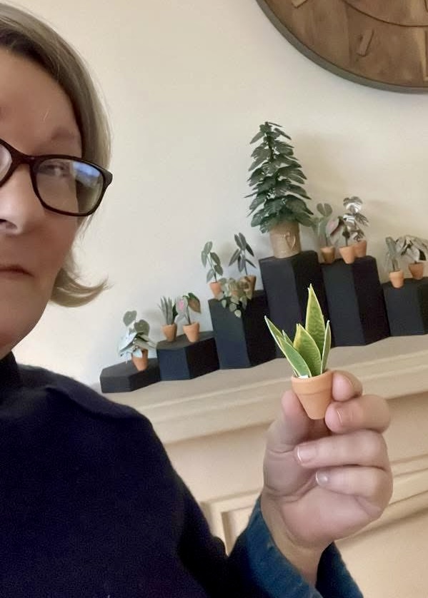 Miniature Sansevieria snake plant from Nicole’s Jungle kit Woman holding a miniature handmade paper Sansevieria snake plant, with a display of other paper plants in the background