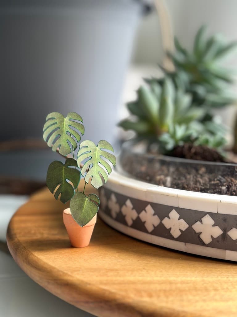 A paper plant on a table next to real plants