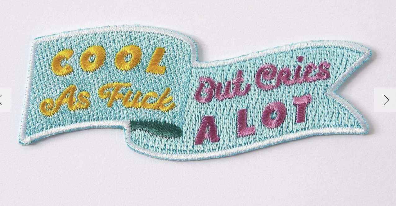 iron on patch of blue banner with pink and yellow text which says 'cool as fuck but cries a lot'