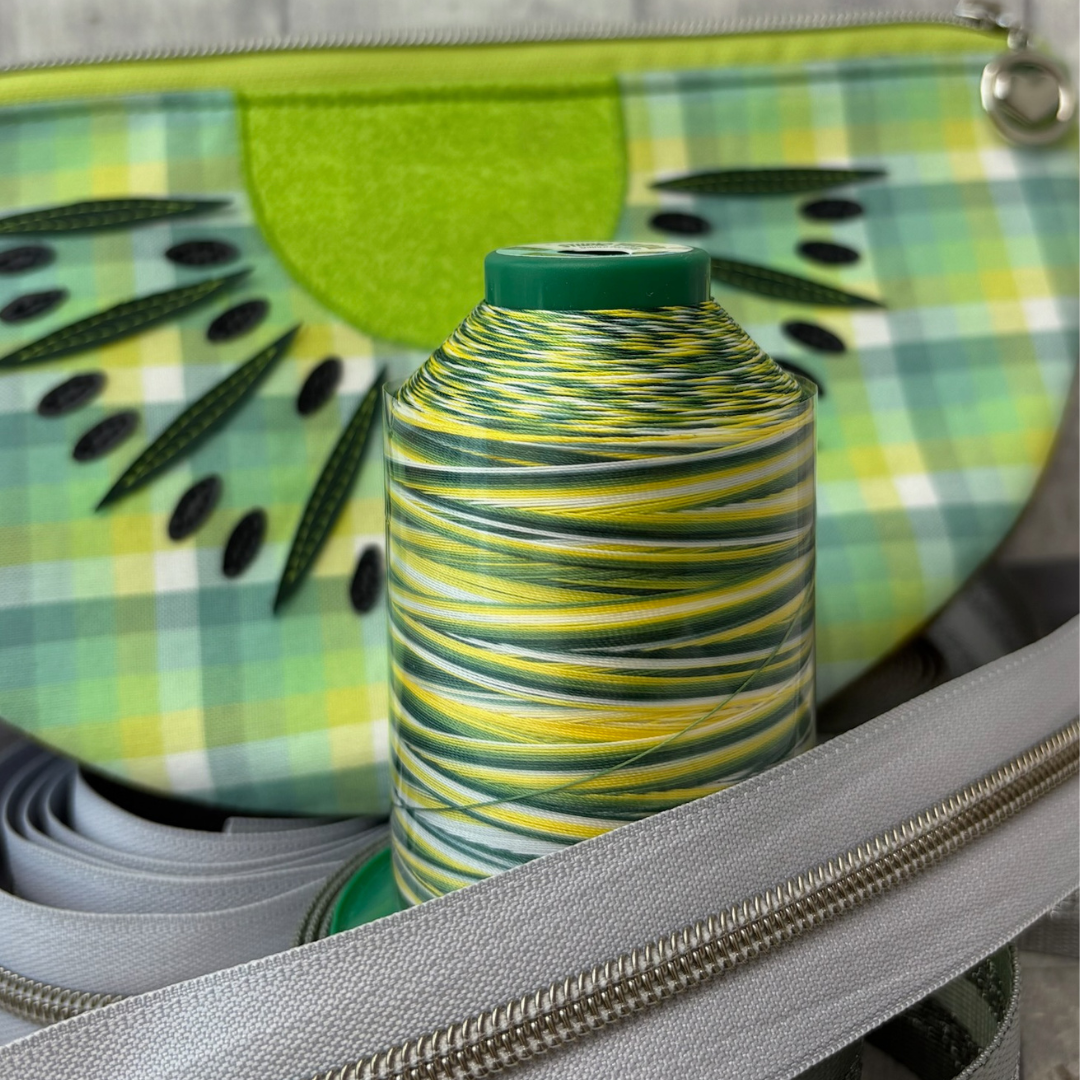 Green and yellow variegated thread with matching zips and a kiwi-themed bag in the background.
