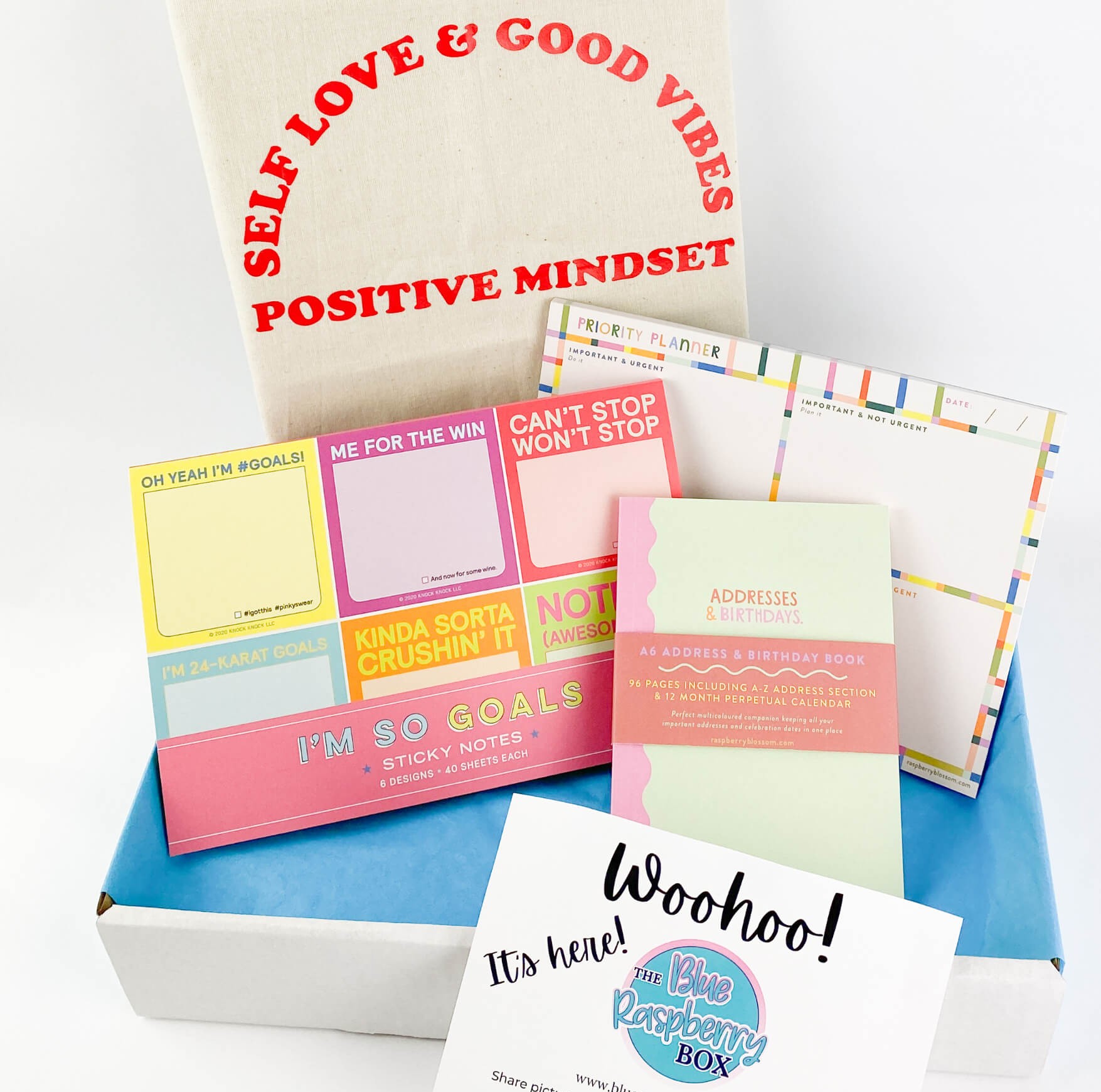 White box containing bright home office stationery items and canvas bag saying 'Self love and good vibes. Positive mindset.