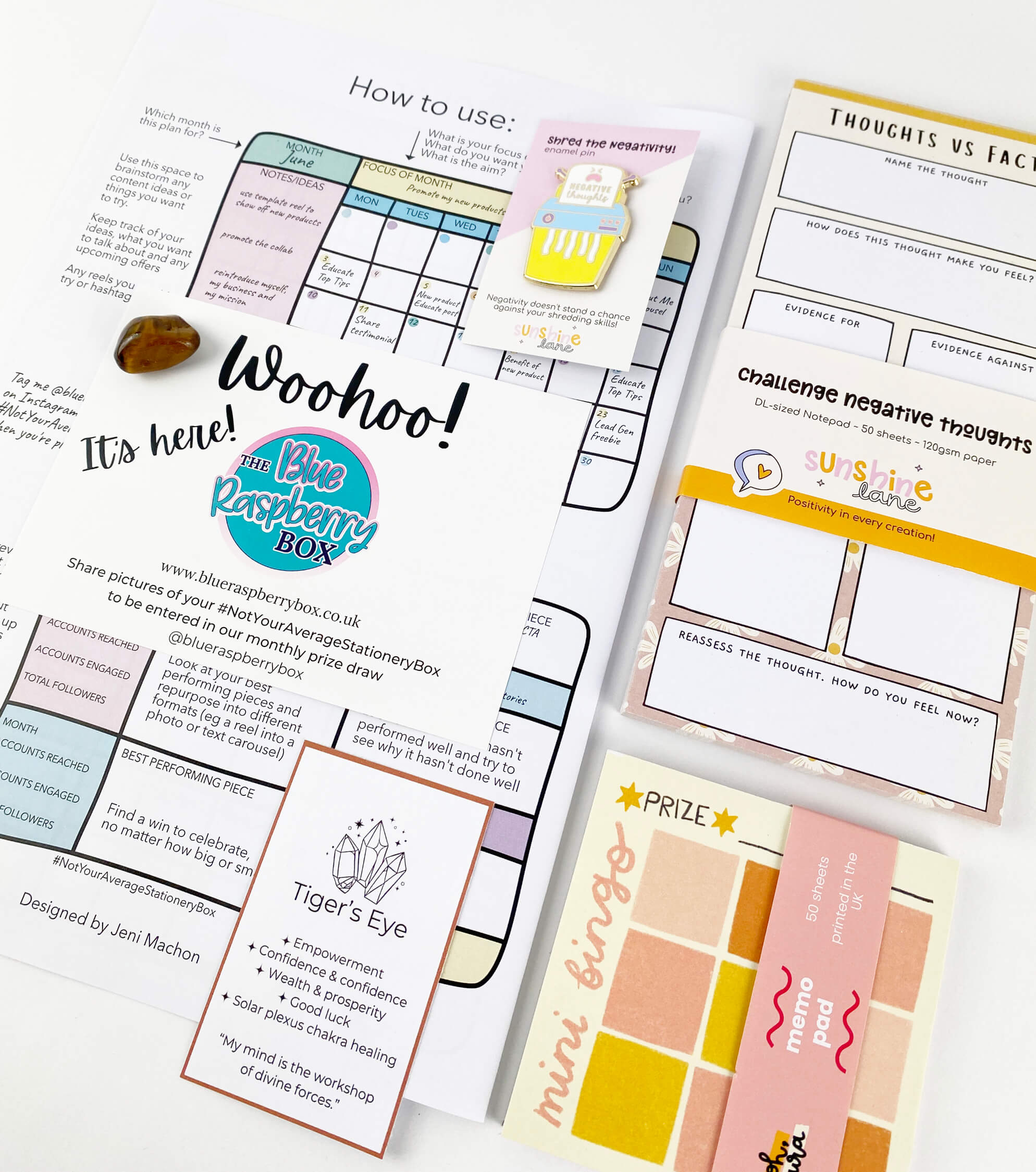 Mindset notepad, fun memo pad next to a social media wall planner with crystal and enamel pin on a white desk