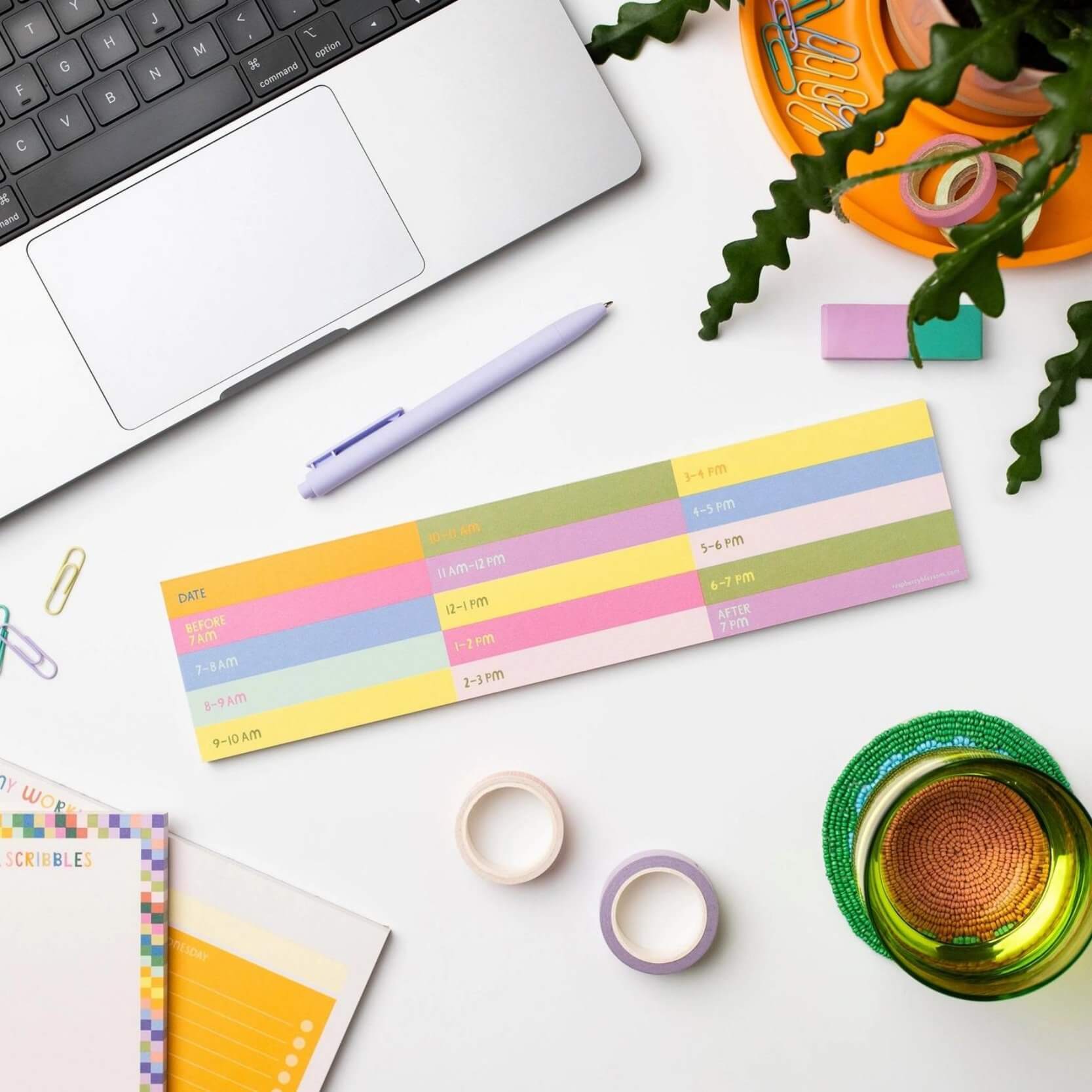 Time blocked keyboard pad on a white desk with laptop, surrounded by stationery items